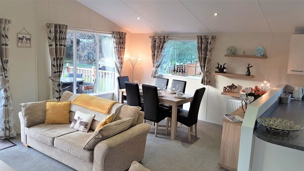 A cozy living room with a sofa and a dining area with a table and chairs. - Little Fawn Felmoor Park (Morpeth)