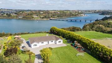 A house with a large lawn, a play area, and a view of a river with a bridge.