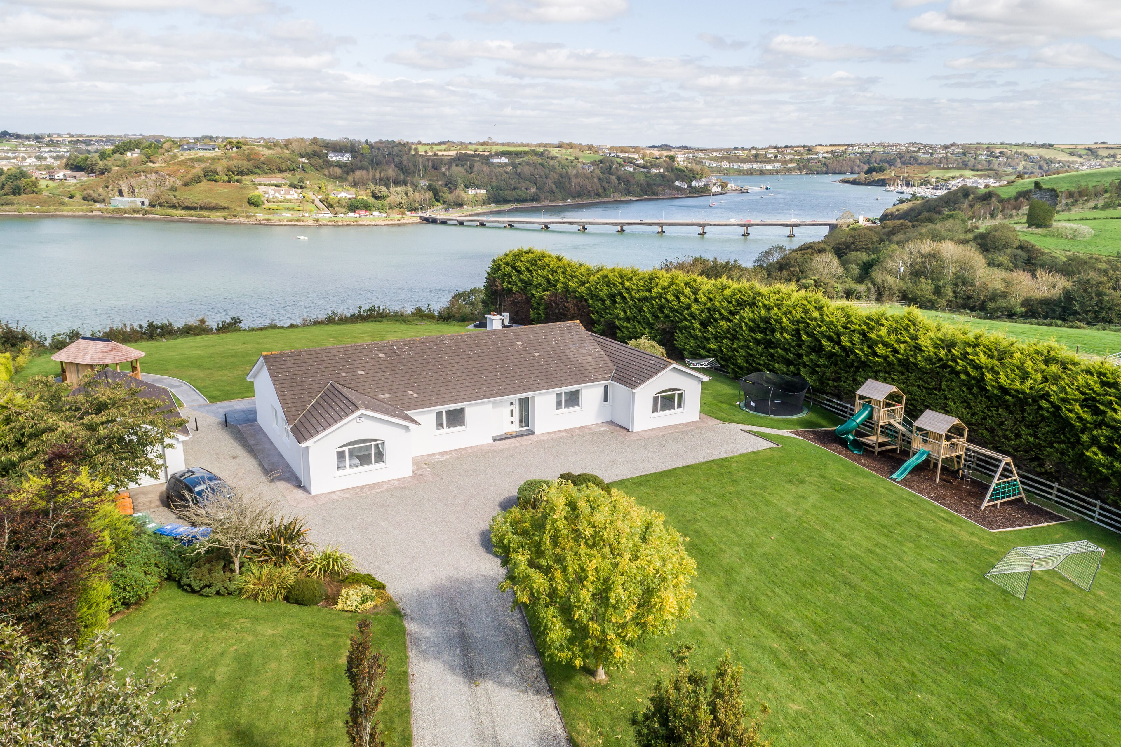 A house with a driveway, a lawn, and a playground with slides.