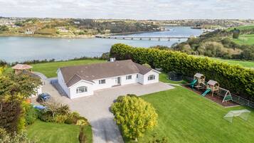 A house with a driveway, a lawn, and a playground with slides.