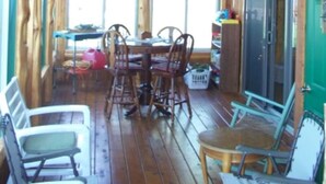 Une cabane en bois comprenant un coin repas, des chaises, une table et un ventilateur de plafond.