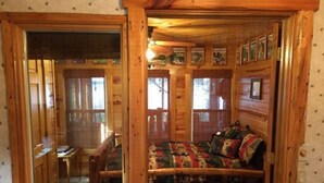 L’intérieur chaleureux d’un chalet avec un lit en bois, une petite table et une fenêtre donnant sur une terrasse.