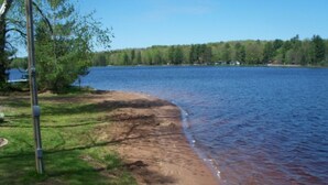 Une vue sur le lac, avec une zone herbeuse, un poteau métallique et un ciel dégagé.