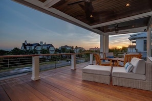 Relax in a covered outdoor space with a sofa and chairs, surrounded by a view of the surrounding landscape.