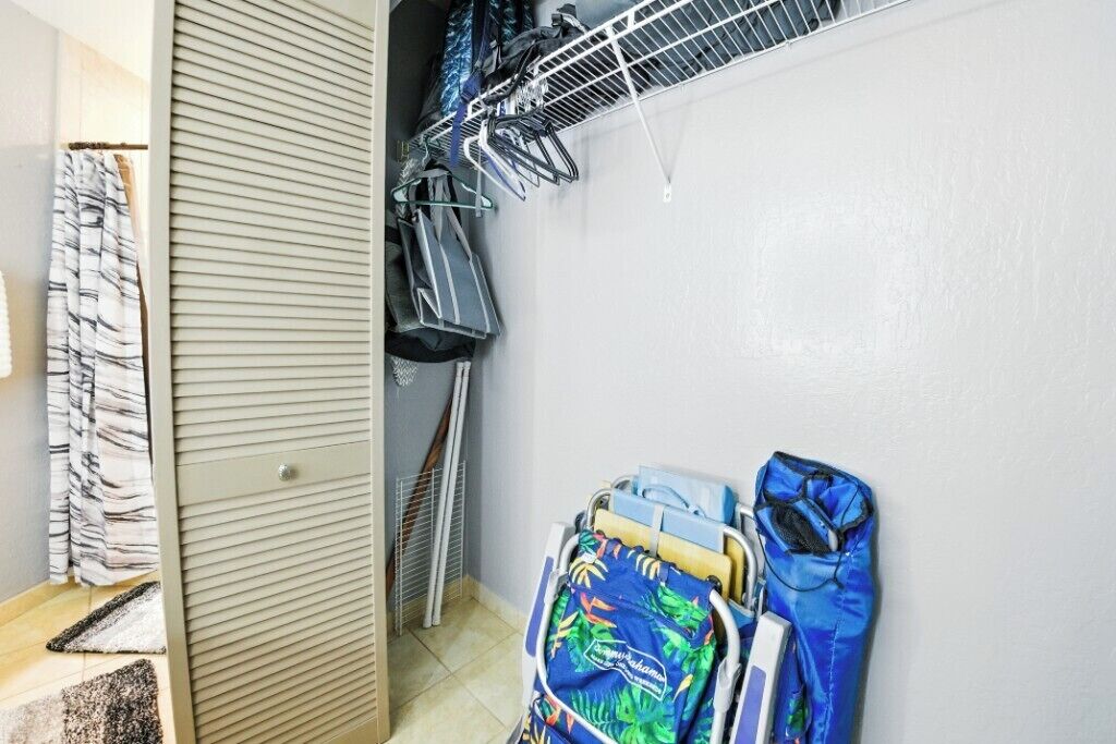 A laundry area with a drying rack, a clothes hamper, and a storage cabinet.