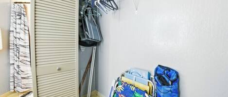 A laundry area with a drying rack, a clothes hamper, and a storage cabinet.