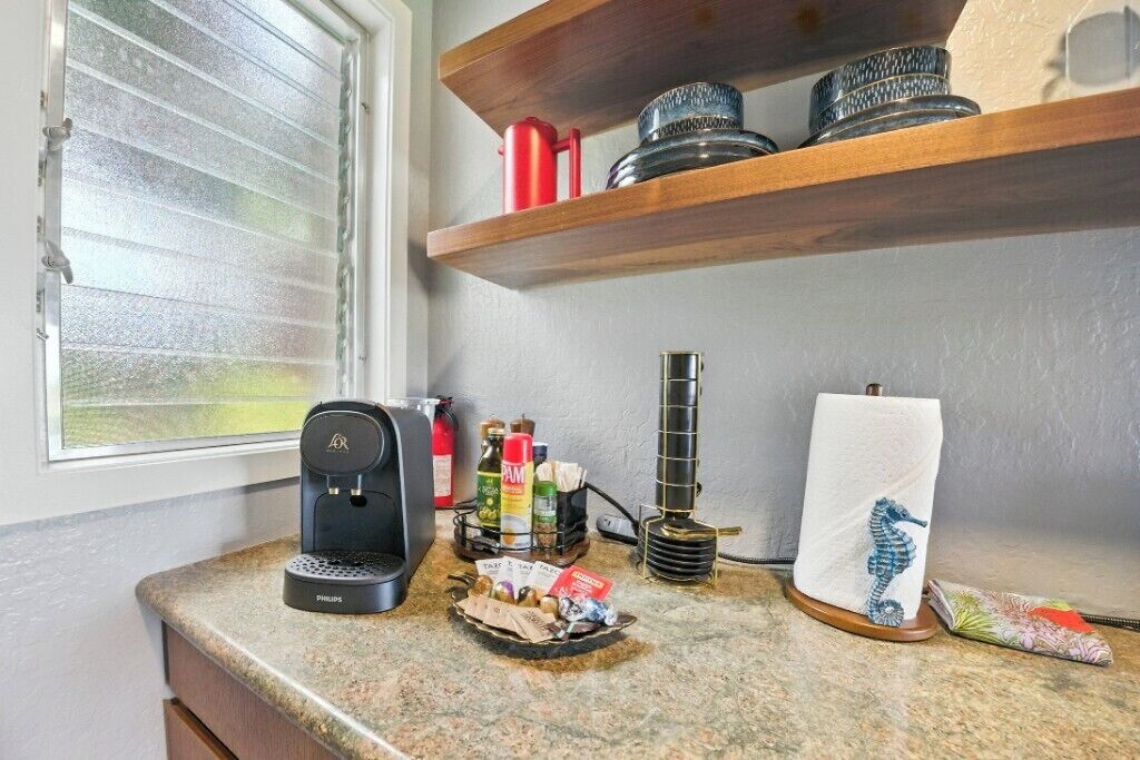Una encimera de cocina con una cafetera, un hervidor de agua y diversos utensilios de cocina.