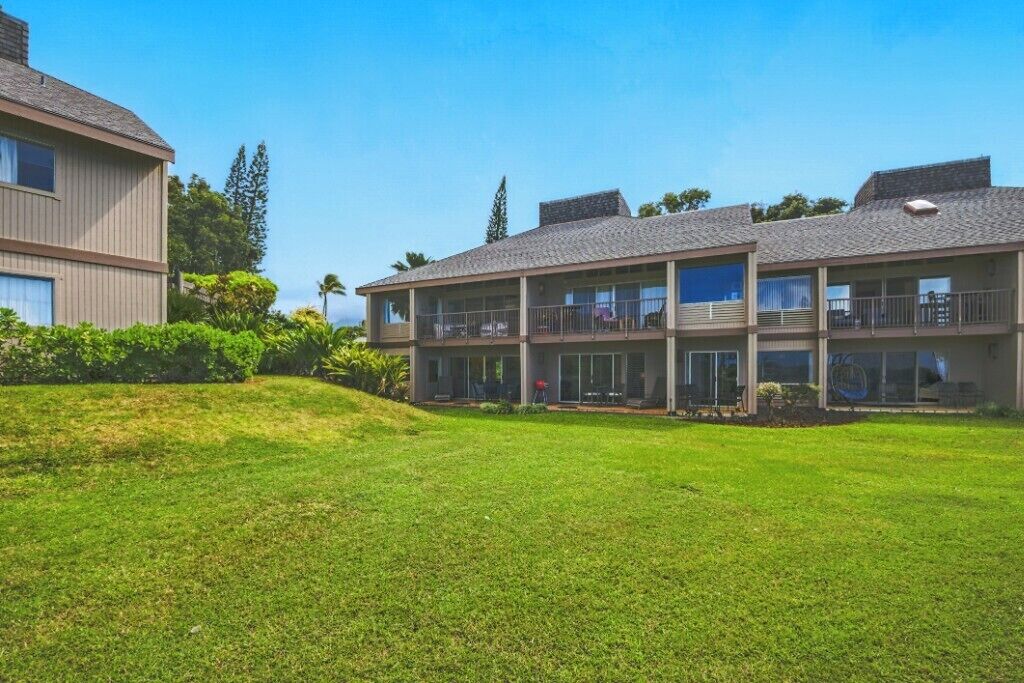 A multi-story hotel with a flat roof, large windows, and a grassy lawn.