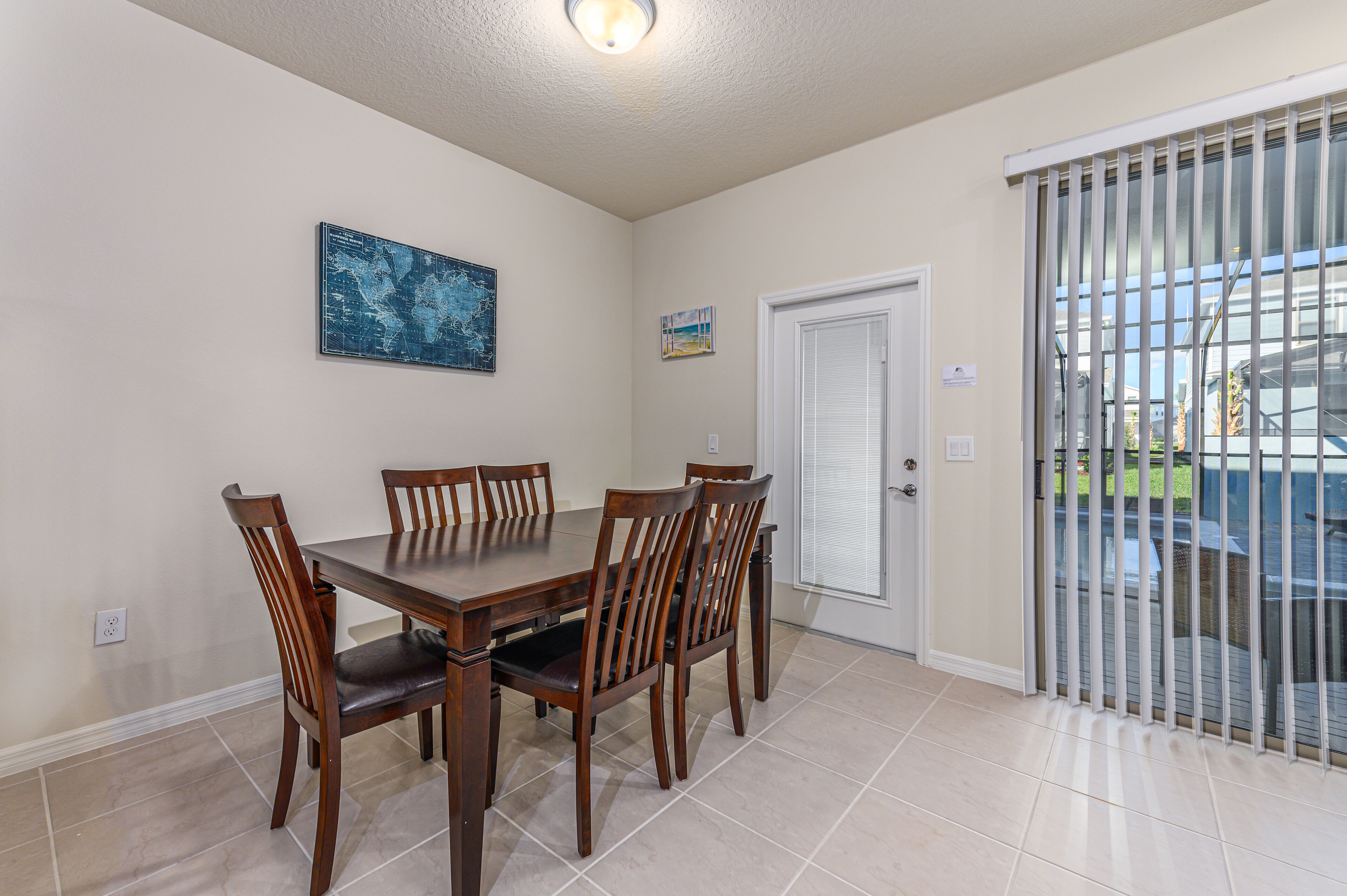 A dining area with a wooden table and chairs, a door with a window, and a tiled floor.