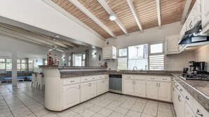 Eine geräumige Küche mit weißen Schränken, einer Granitarbeitsplatte und einem Deckenventilator.