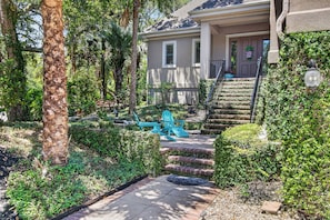 A house with a front porch, steps leading to the entrance, and a small garden area with a bench and chair. - Award-Winning Resort Amenities | Fairway Oaks 42 (Isle of Palms)