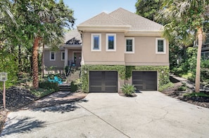 A two-story house with a garage, a front yard with a palm tree, and a staircase leading to a porch. - Award-Winning Resort Amenities | Fairway Oaks 42 (Isle of Palms)
