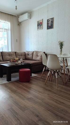 Relax in this stylish living room with a comfortable sofa, dining table, and beautiful vase with fresh flowers.