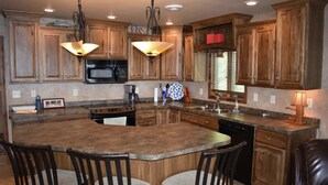 A kitchen with wooden cabinets, a large island with bar stools, a microwave, a stove, and pendant lighting. - 30 steps to lake, Dock for fishing & swimming, Families Welcome!   (Miltona)