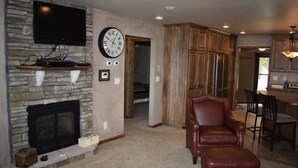 A living room with a stone fireplace, a leather armchair, a dining area with wooden cabinets, and a kitchen with a wooden countertop. - 30 steps to lake, Dock for fishing & swimming, Families Welcome!   (Miltona)