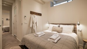 Une chambre avec un grand lit, une lucarne, une table de chevet et un porte-serviettes fixé au mur.