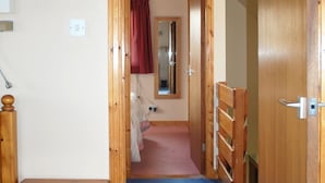 Un couloir avec des portes en bois, un miroir, un rideau rouge et une moquette bleue.