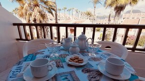 A balcony table set with white teapots, cups, and a plate of cookies, overlooking a cityscape with palm trees and buildings. - Americas II Holiday Home (Playa de las Américas)
