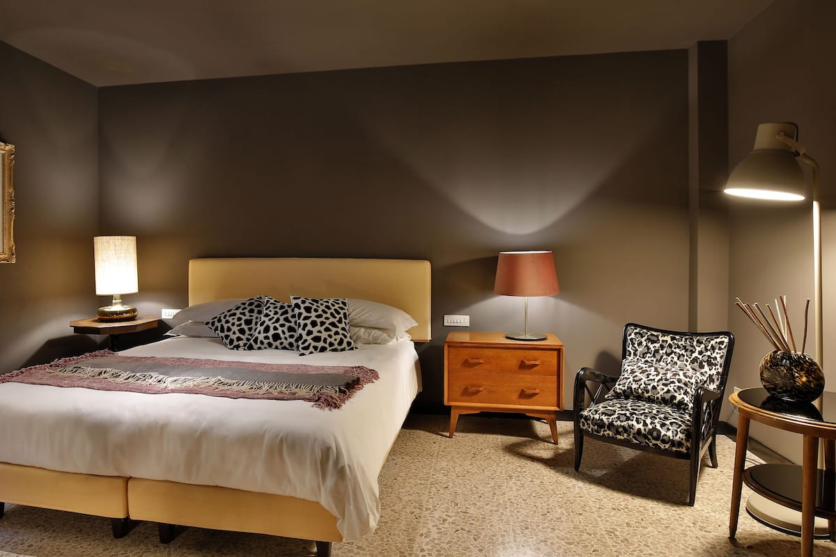 Een hotelkamer met een bed, twee nachtkastjes, een stoel en een lamp.