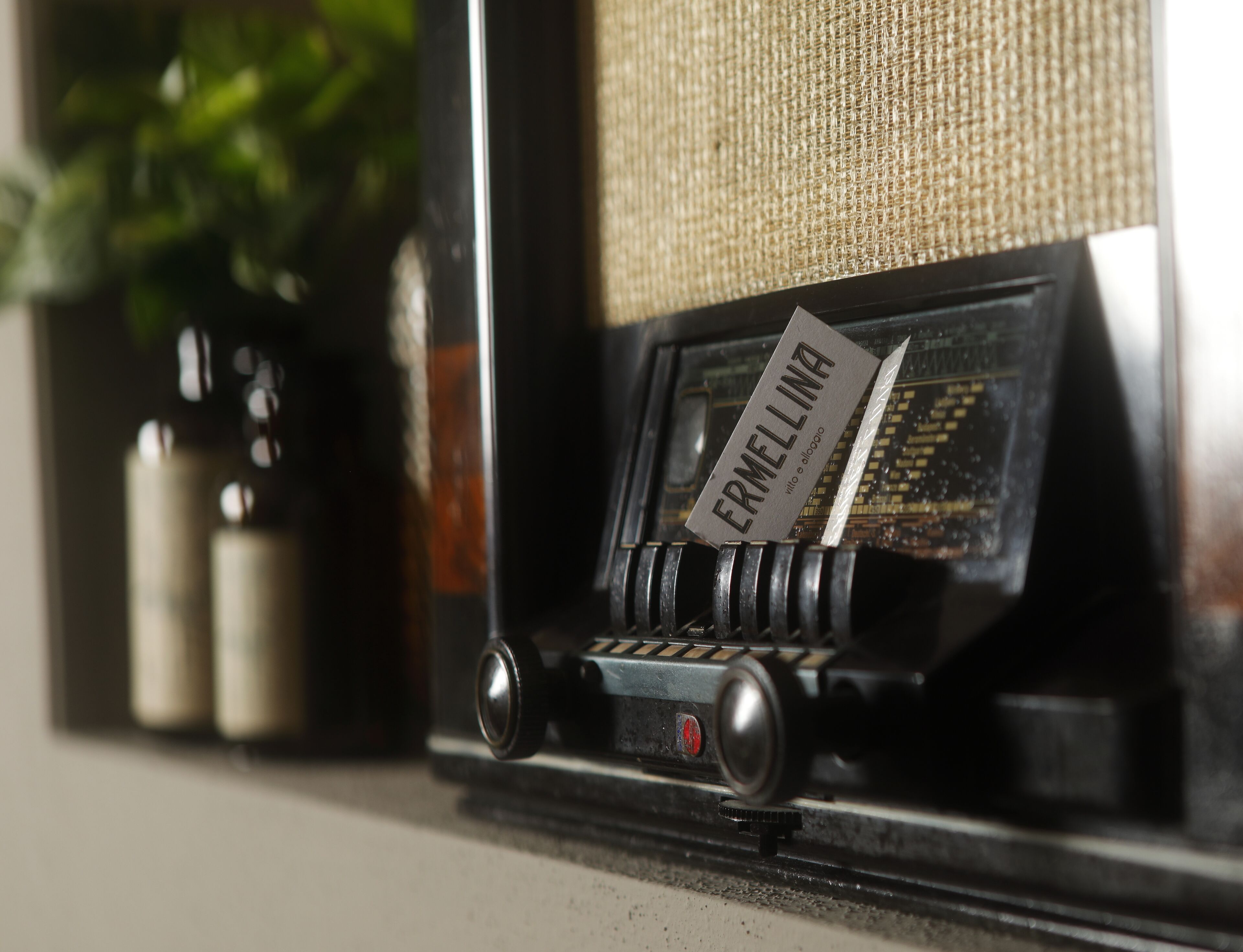 A vintage radio with a label reading "ERMELINA" on a shelf.