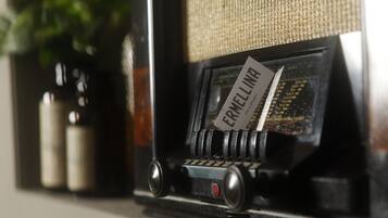 A vintage radio with a label reading "ERMELINA" on a shelf.