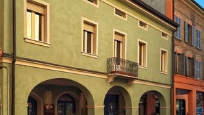 Un edificio con fachada verde, varias ventanas y un balcón.