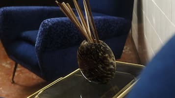 A smartphone on a glass table with a decorative vase containing reed sticks.