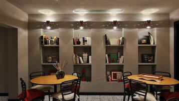 Una habitación con dos mesas redondas, cada una rodeada de sillas, y estanterías contra la pared.