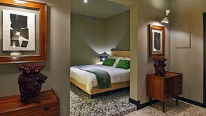Una habitación de hotel con una cama, un aparador y una obra de arte enmarcada en la pared.