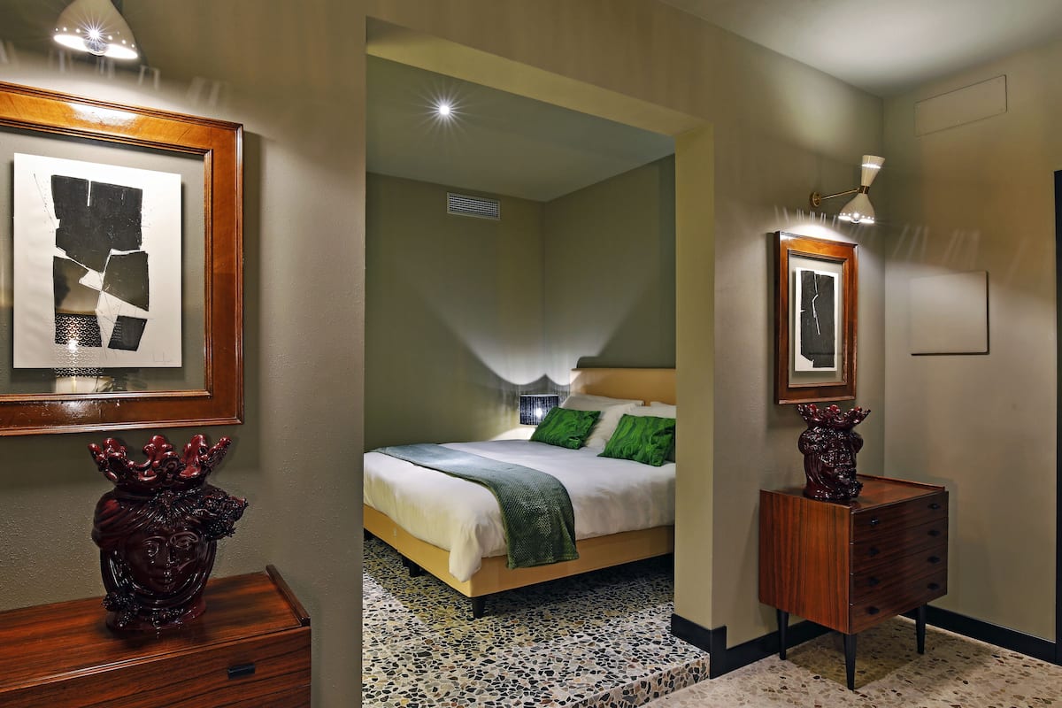 Een hotelkamer met een bed, een dressoir en een kunstwerk in een lijst aan de muur.