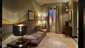 Un salón acogedor con sofá, una lámpara y vistas al exterior a través de una ventana con cortinas.