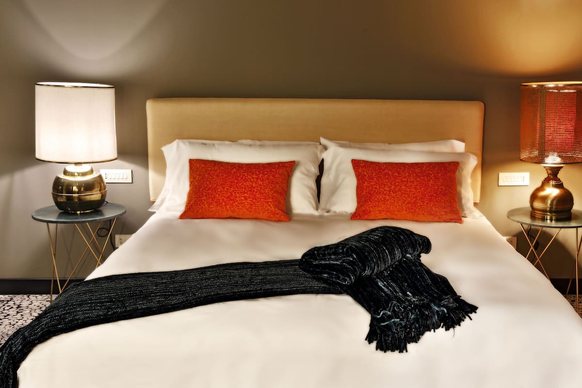 Een hotelkamer met een bed, twee nachtkastjes en twee lampen.