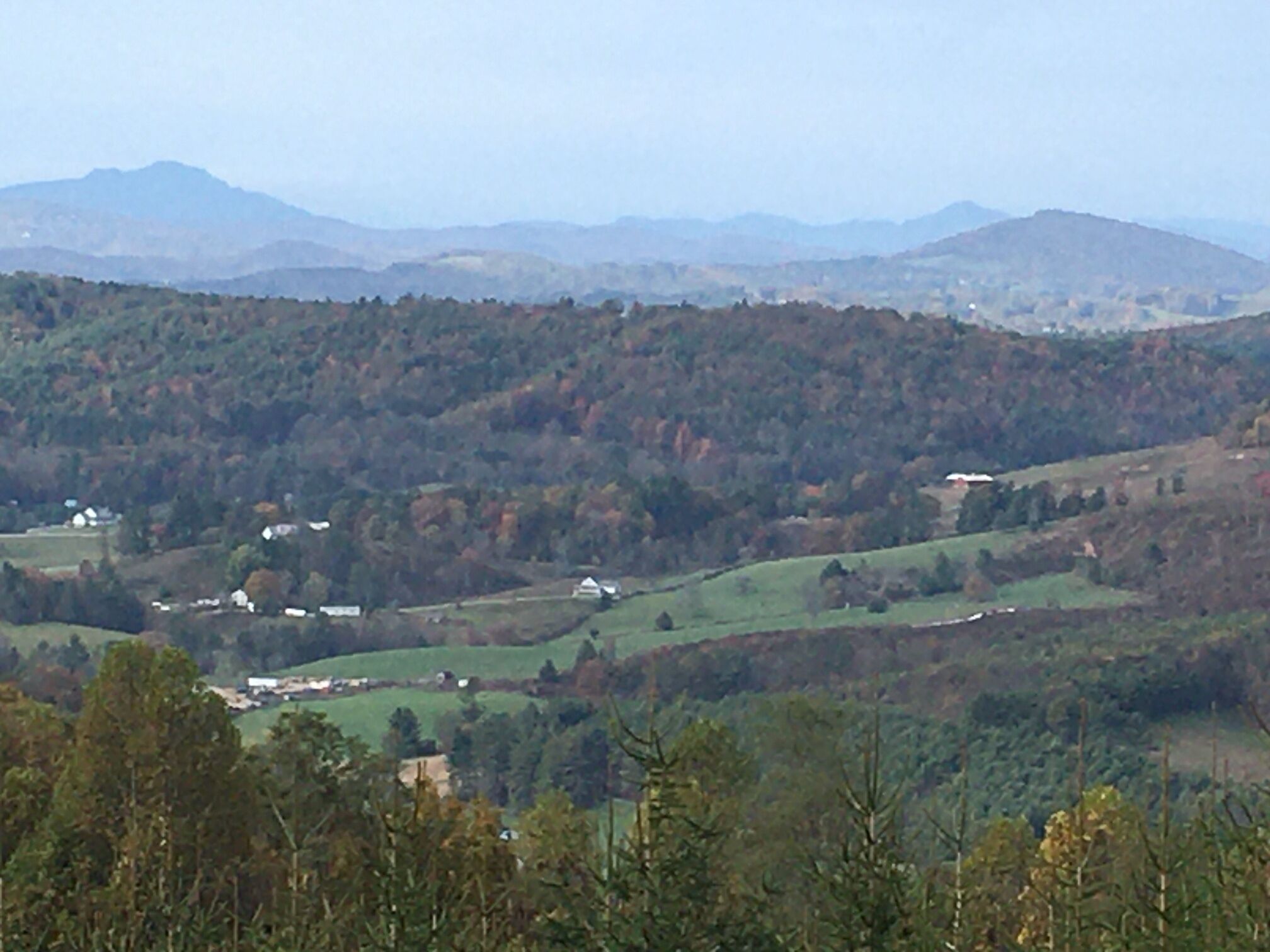 Ein weiter Blick über eine hügelige Landschaft mit verstreuten Gebäuden, vermutlich ein ländliches Gebiet.