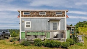 A two-story house with a front porch, a car parked in the driveway, and a green fence.