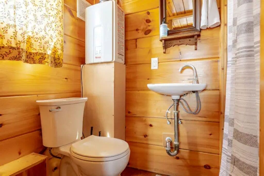 Ein kleines Badezimmer aus Holz mit Toilette, Waschbecken und Dusche.