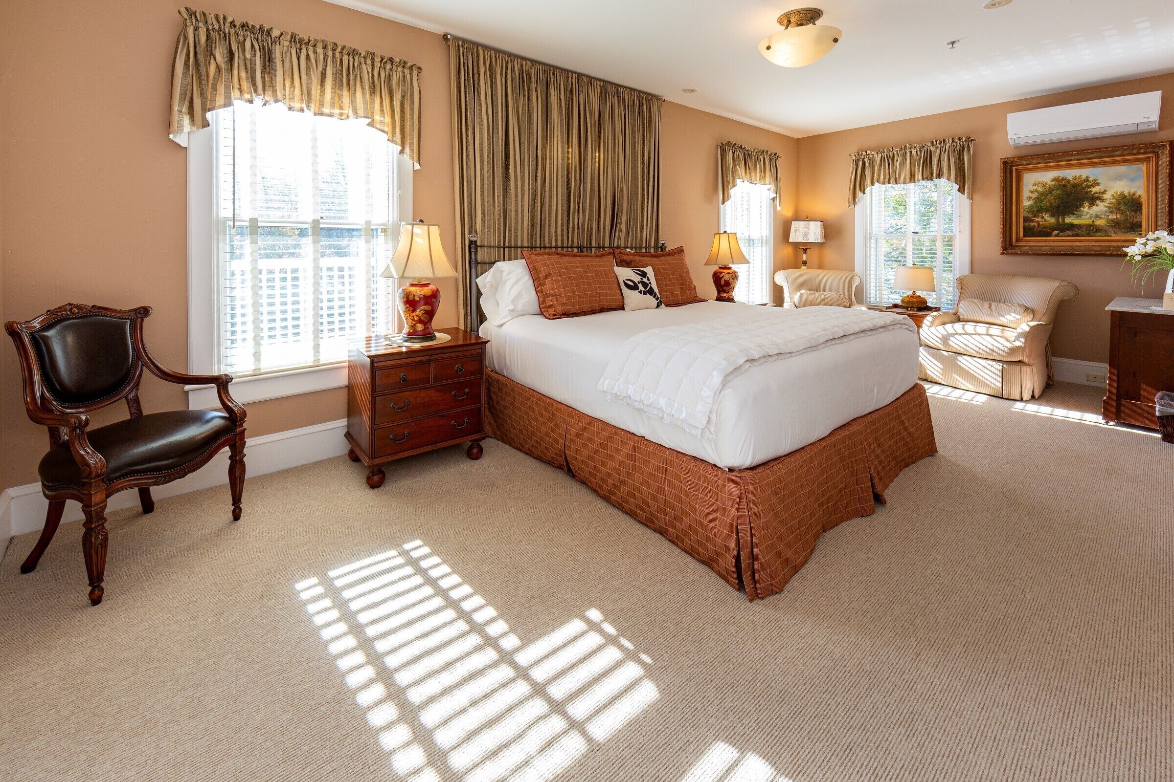 A spacious bedroom with a large bed, two bedside tables, a chair, and a dresser.