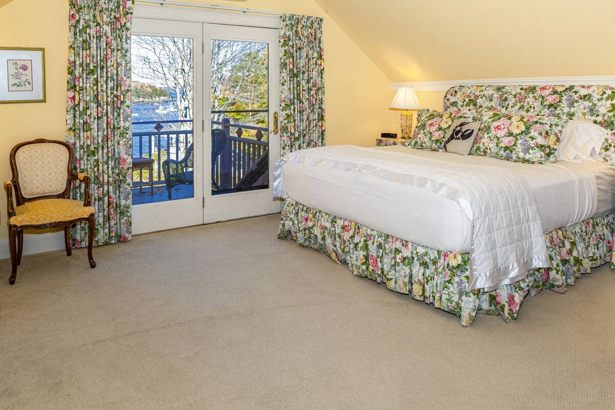 A bedroom with a bed, a chair, a nightstand, and a view of a balcony.