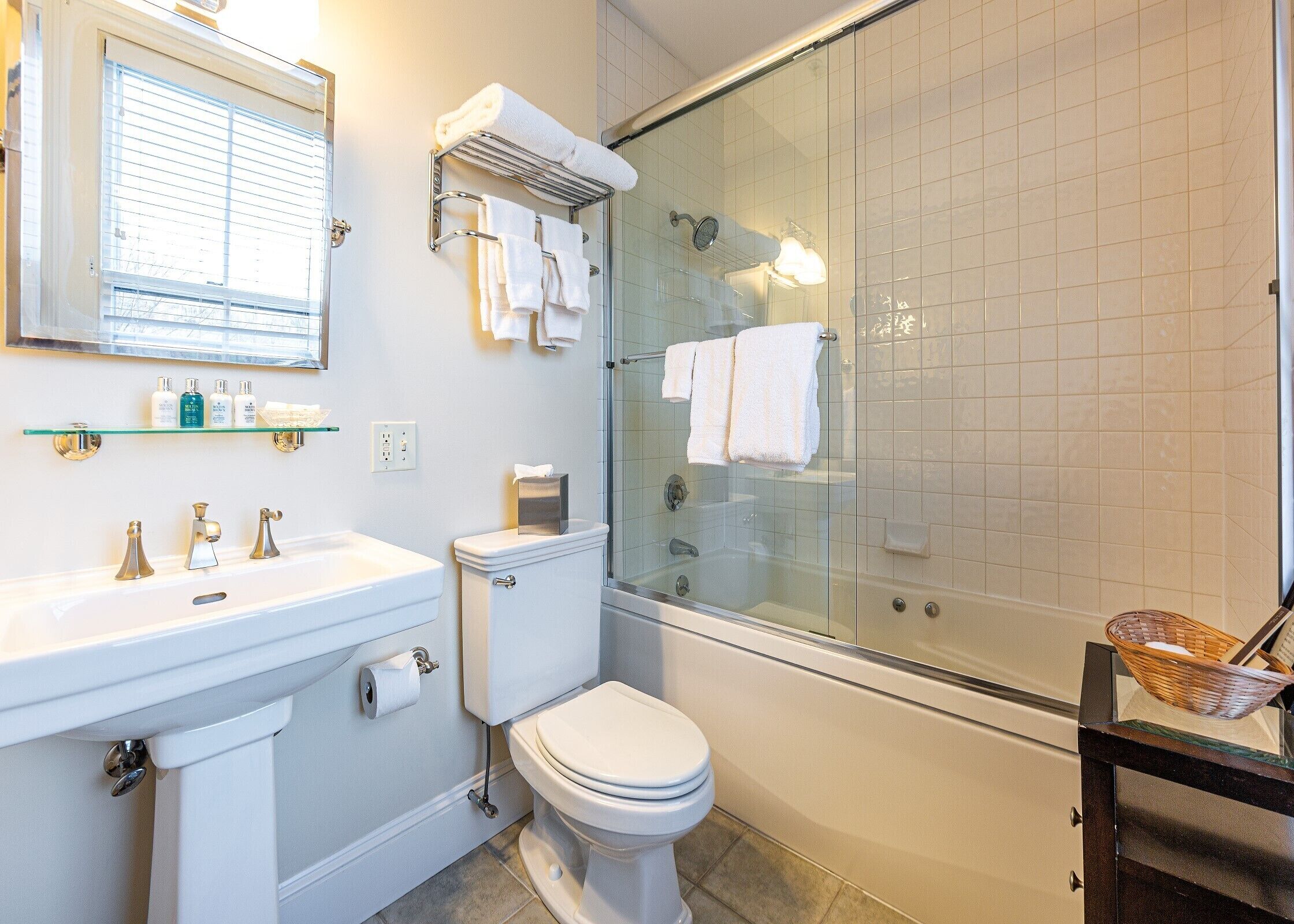 A modern bathroom with a glass-enclosed shower, a white toilet, and a vanity with a mirror and shelf.
