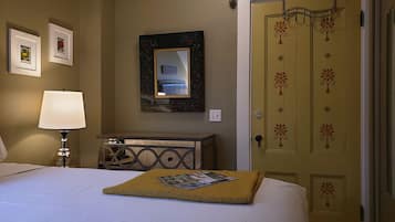 A hotel room with a bed, a bedside lamp, a dresser, a mirror, and a door with floral decorations.