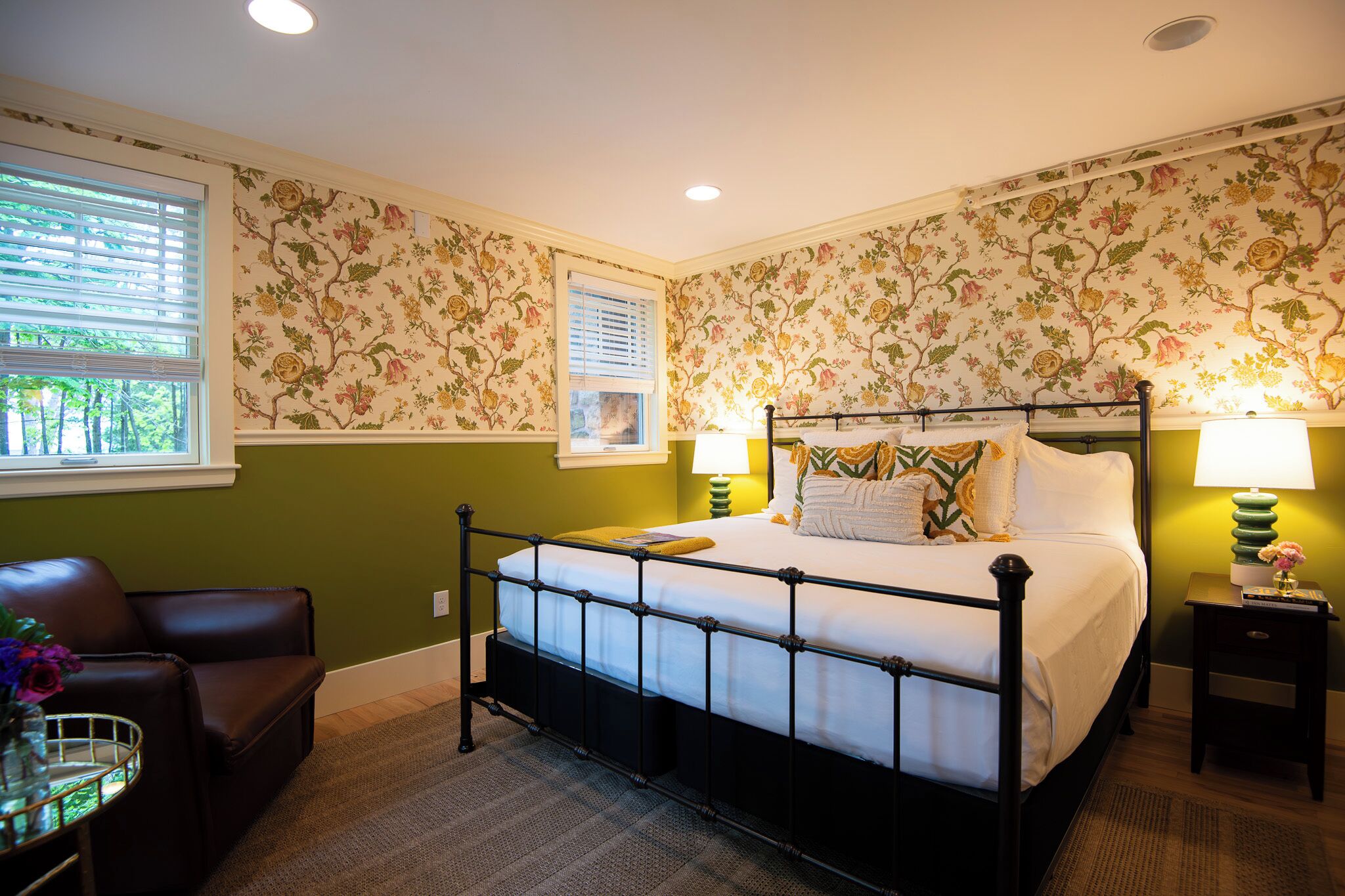 Un dormitorio con cama con dosel, una ventana con persianas, pared verde y papel tapiz floral.