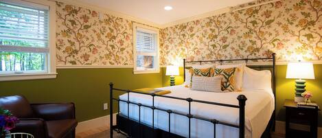 Un dormitorio con cama con dosel, una ventana con persianas, pared verde y papel tapiz floral.