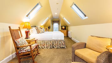 Un dormitorio cálido en el ático, con una cama grande, un sillón mecedora, un sofá y un televisor.