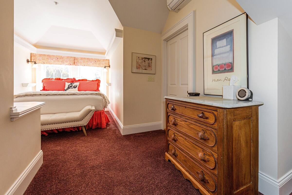 A bedroom with a bed, a dresser, and a framed picture on the wall.