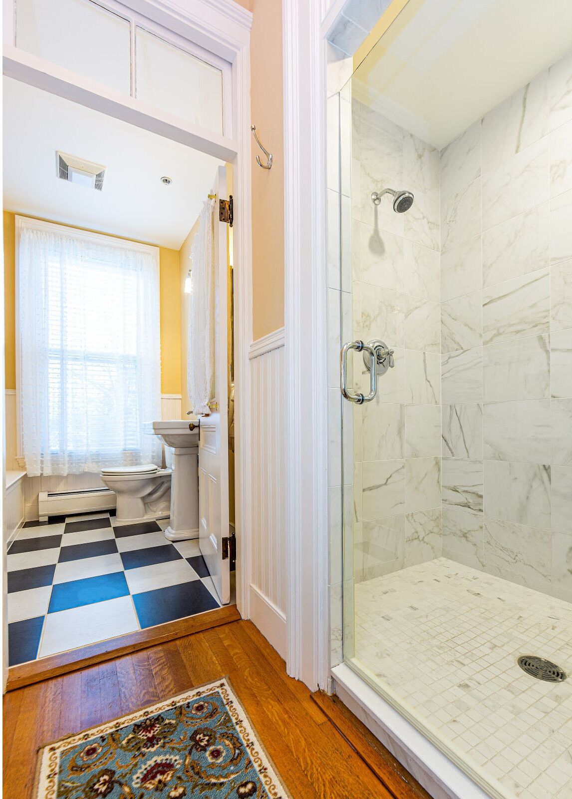 A bathroom with a checkered floor, a glass shower enclosure, and a toilet.