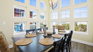 Un espace repas comprenant une grande table, plusieurs chaises et un lustre.