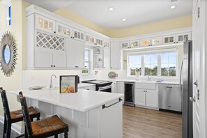 Una cucina moderna con mobili bianchi, un'isola grande e vista dalla finestra.