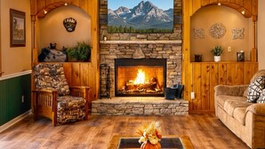 Un salón acogedor con chimenea de piedra, paneles de madera y un cuadro con vistas a la montaña.