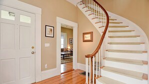A wooden staircase with beige carpeted steps and white walls.