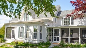A two-story house with a covered porch and a garden.