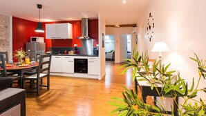 A modern kitchen with white cabinets, a stainless steel range hood, and a red accent wall.